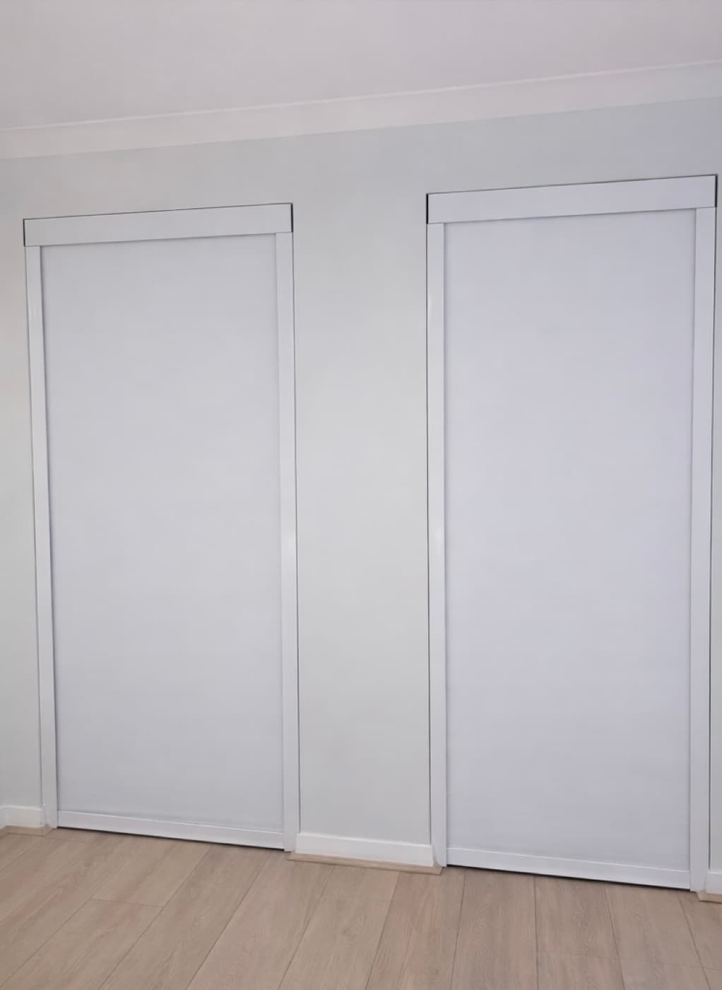 Two blackout blinds side by side, one closed and one slightly open, showing the seal at the bottom rail.