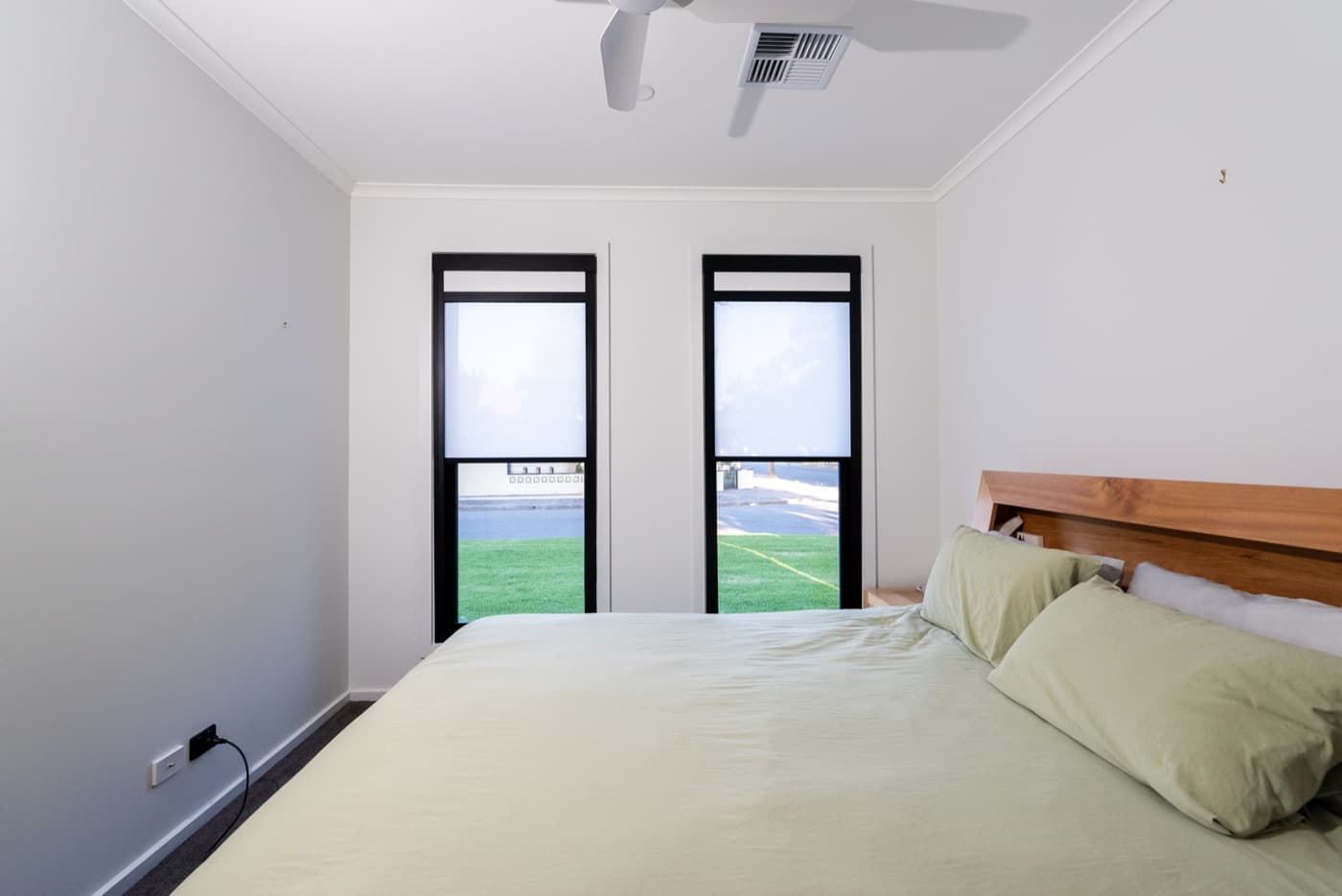 Two black-frame blackout blinds side by side in a bedroom.