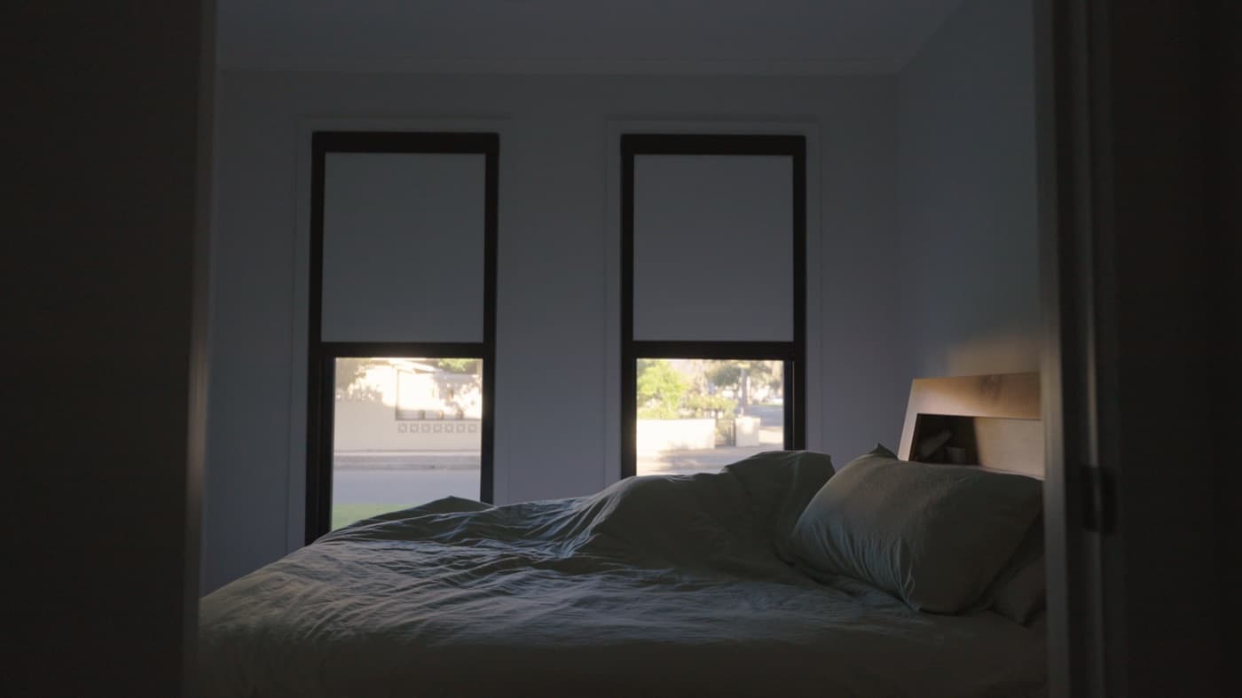 Black-frame blackout blinds two-thirds down at dusk, side tracks visible.