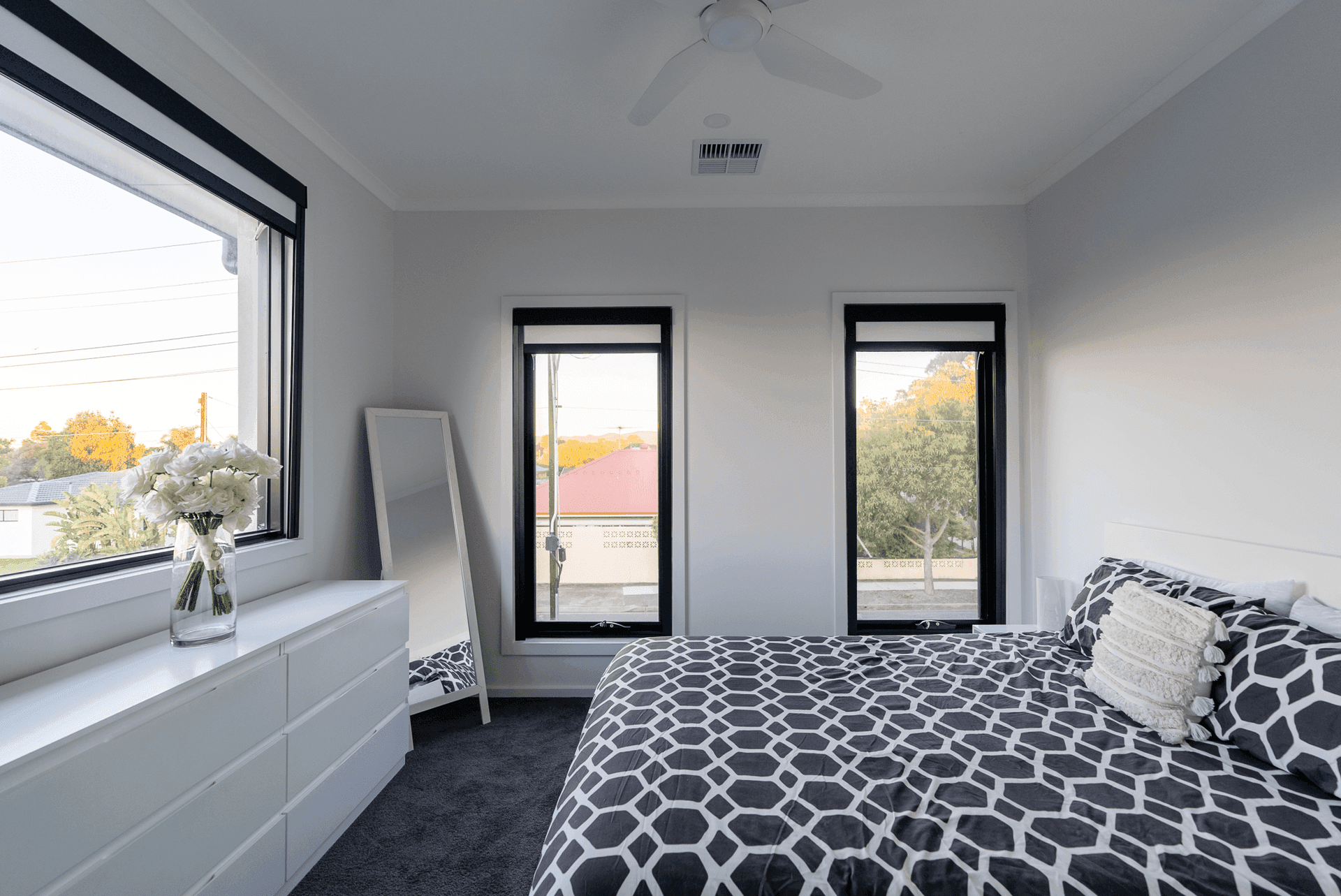 Two black-frame blinds in a bedroom — one open, one closed.
