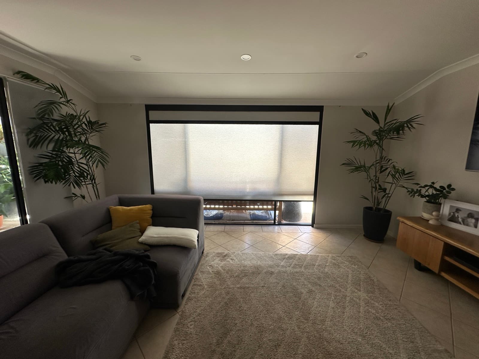 Wide sliding-door opening in a living room with the black-frame blackout blind lowered.