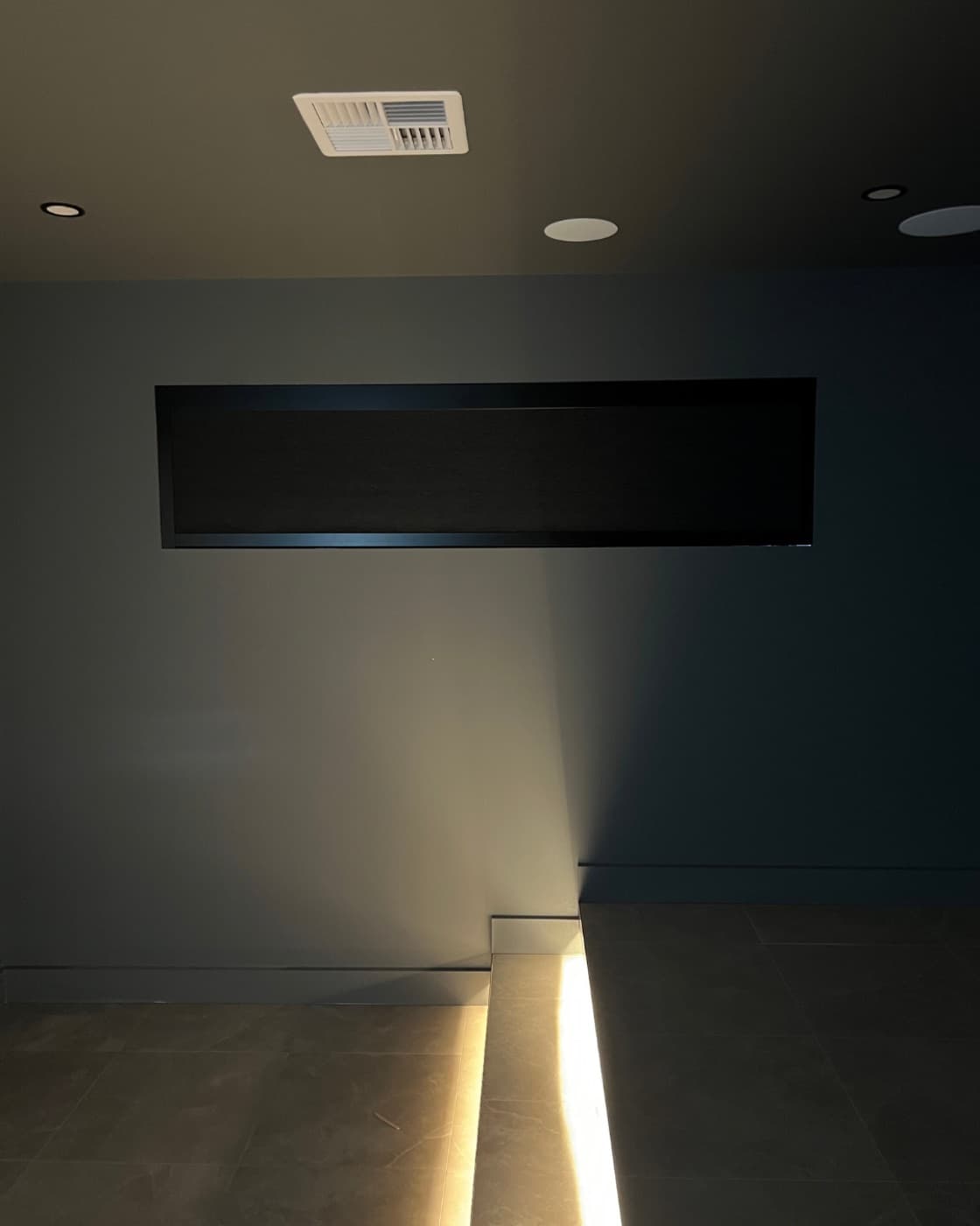 Home theatre in full blackout — the blind sealed shut, only the step lighting glowing.