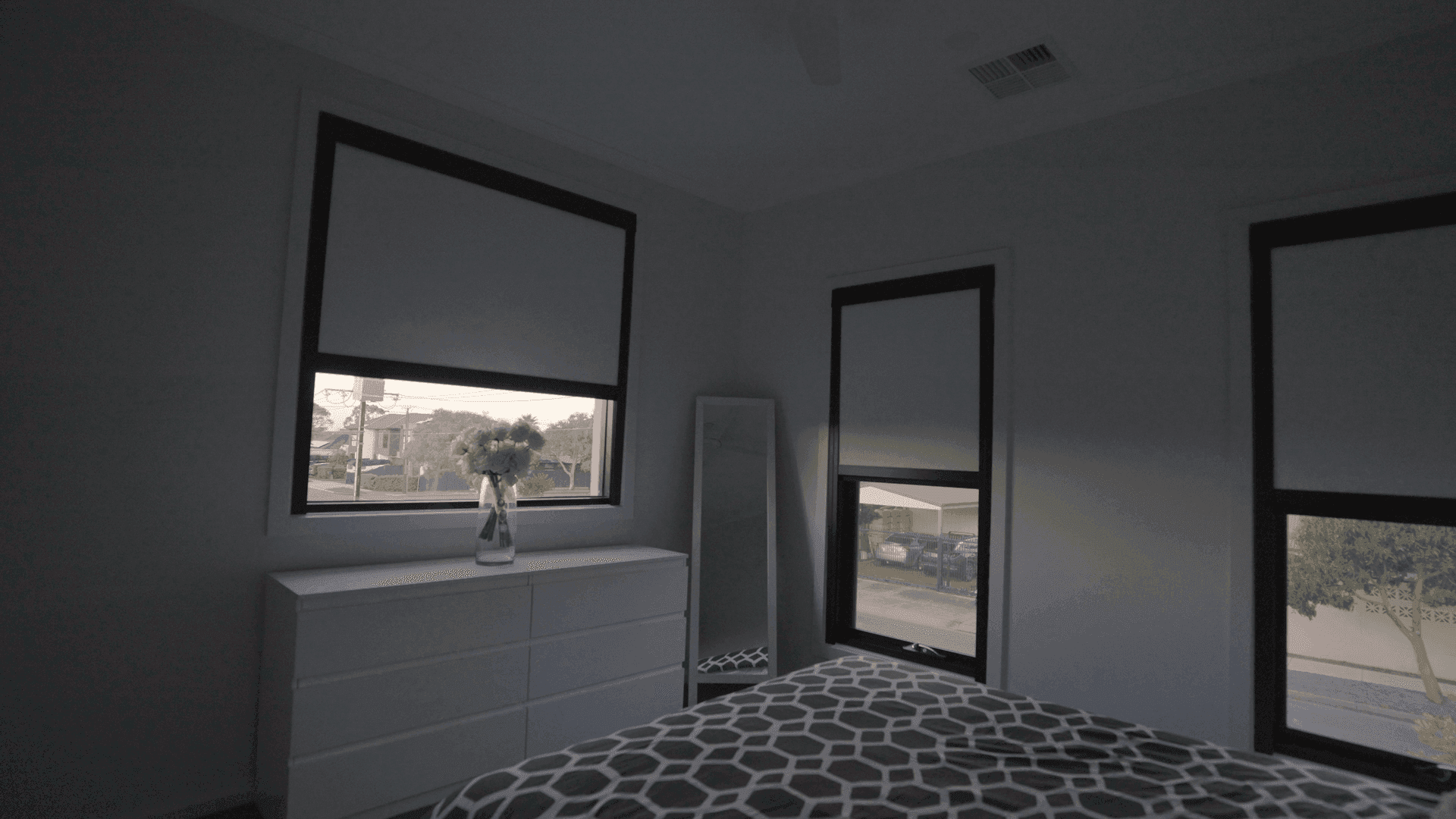 Master bedroom in full daytime blackout — daylight outside, room dark.