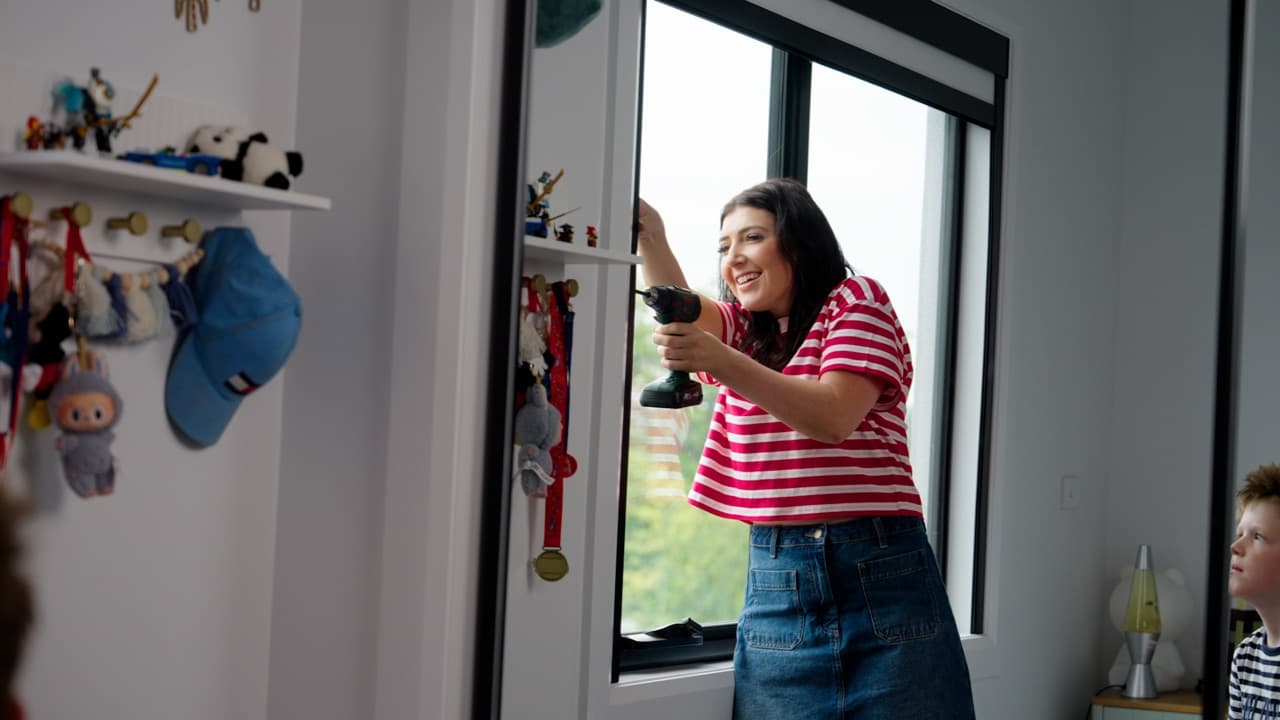 DIY install — fitting a black-frame blackout blind with a cordless drill.