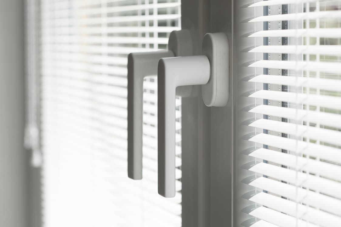 Window handles protruding from the side of a sliding window.