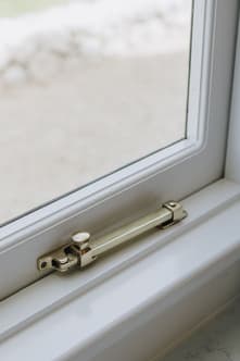 Small window latch on the side of an awning window frame.