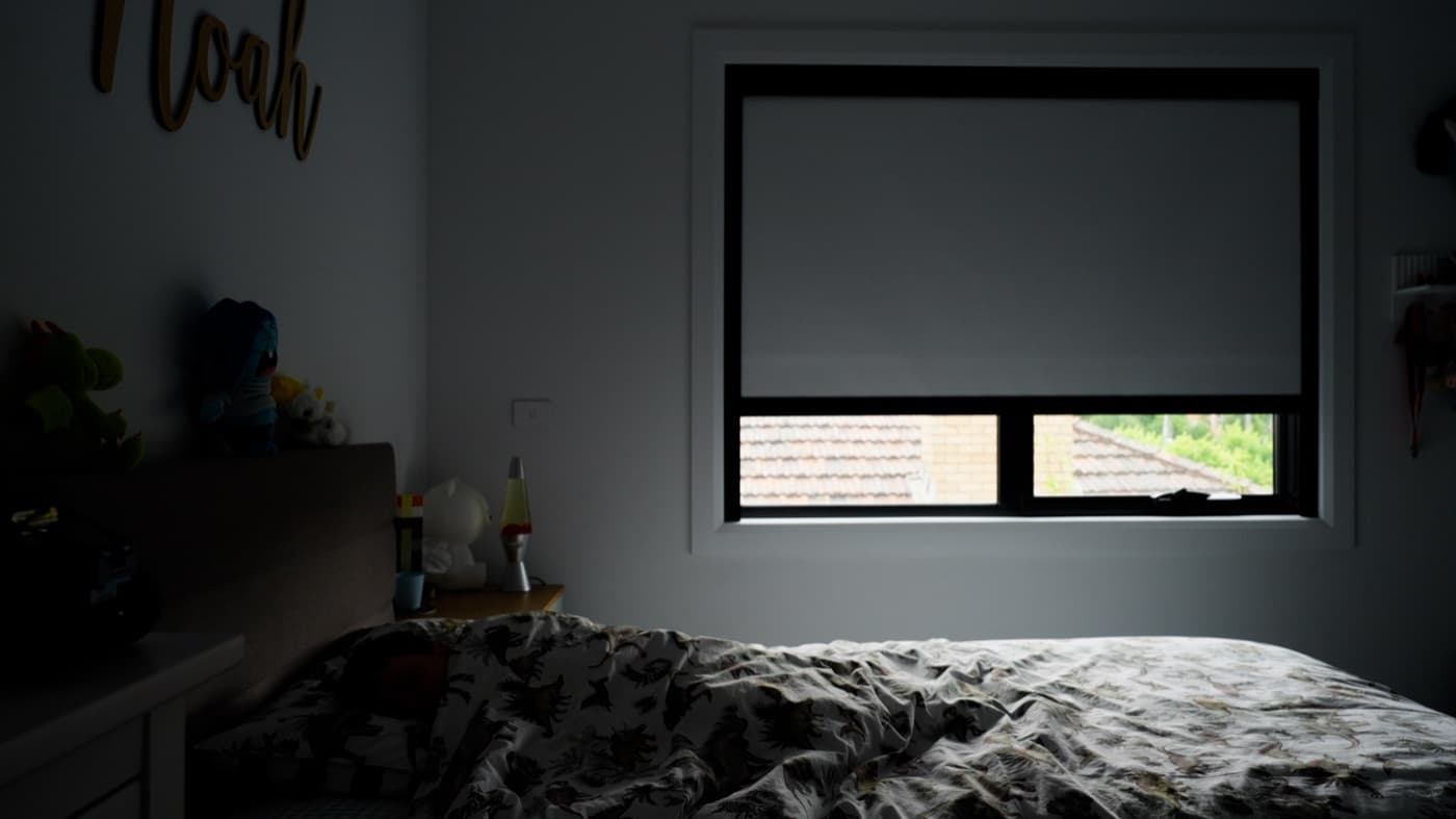 Blackout blind down in a darkened room, sealed at the bottom rail.